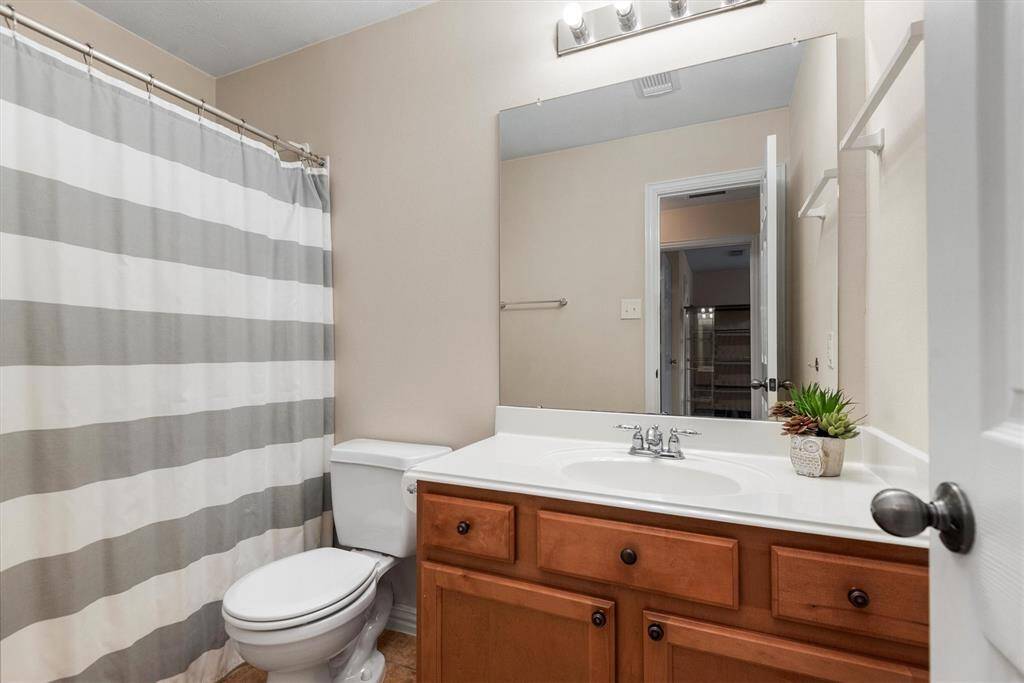 This is a well-maintained bathroom featuring a combination tub and shower with a single sink vanity with ample storage. The space is completed with a large mirror and modern lighting fixtures.