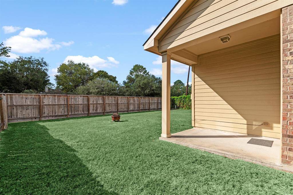 This home showcases a spacious, well-maintained backyard with a lush green lawn and privacy fencing. The covered patio area offers an ideal space for outdoor relaxation and entertainment.