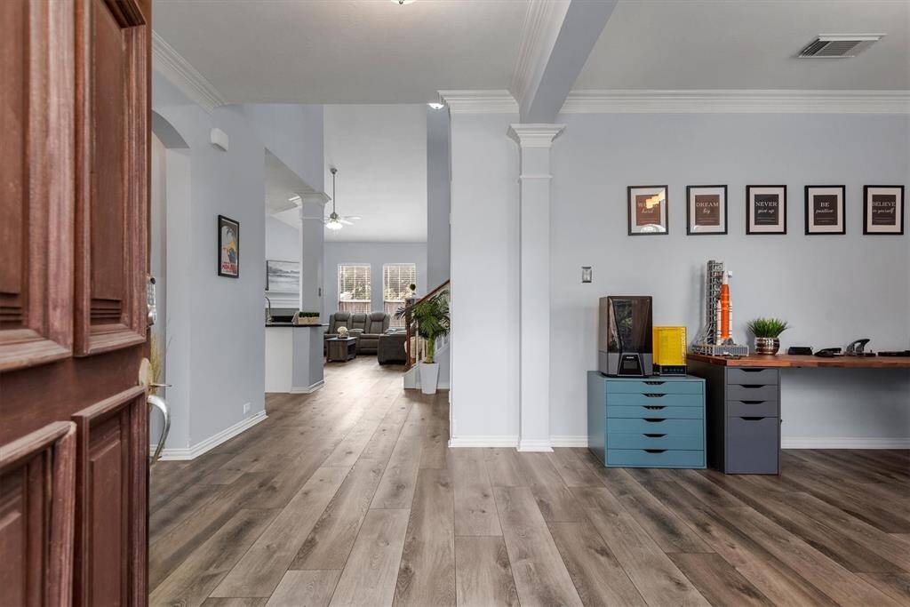 This home features an open and airy living space with elegant vinyl plank wood flooring, crisp neutral walls, and classic columns, creating a modern yet timeless atmosphere. The layout provides a seamless flow between the living, dining, and kitchen areas, ideal for both entertaining and everyday living.