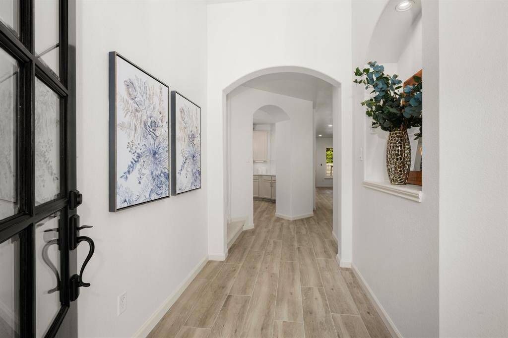 Step into a bright and elegant foyer featuring wood-look tile flooring, soft neutral walls, and stylish decorative accents.