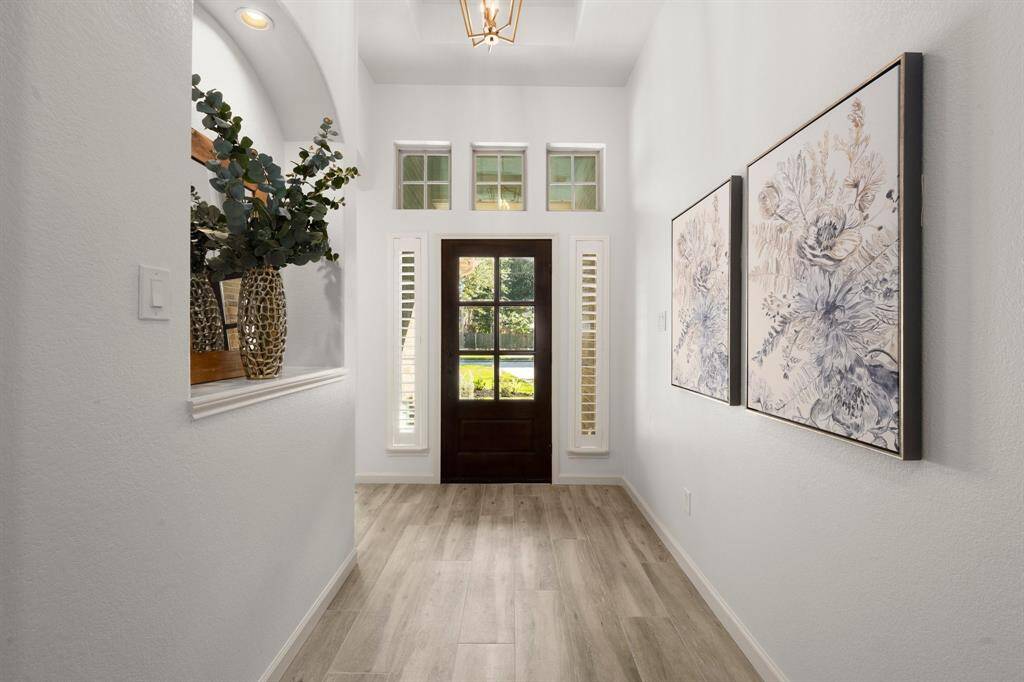 High ceilings, transom windows, and elegant details like plantation shutters and recessed niches add a touch of sophistication to this welcoming space.