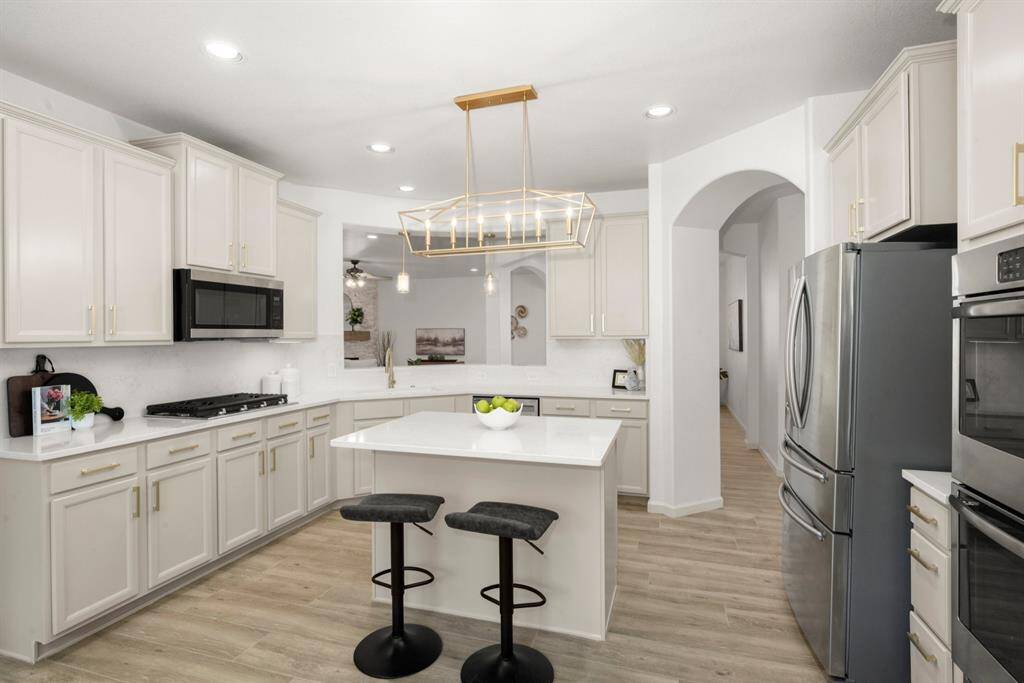 This sleek, updated kitchen features elegant white cabinetry, quartz countertops, and a spacious center island.