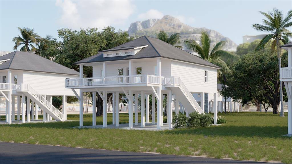 This photo showcases a charming elevated beach house with a wraparound porch, nestled among palm trees and lush greenery, offering a scenic view of the Coast. Ideal for coastal living.