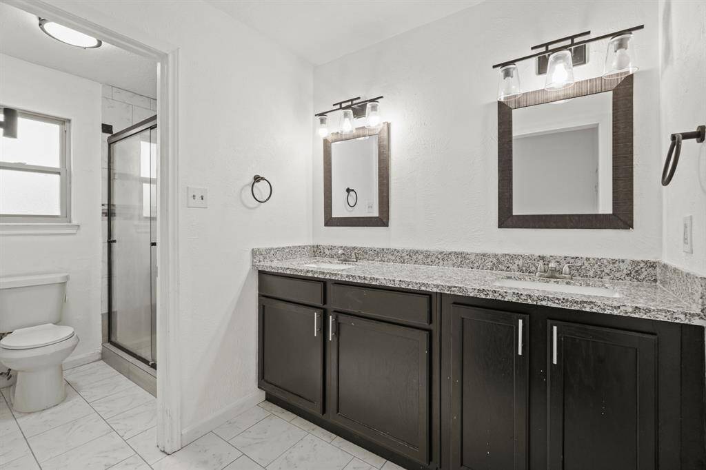 The primary bathroom features tile floors, dual sinks, dark cabinets, and a walk-in shower.