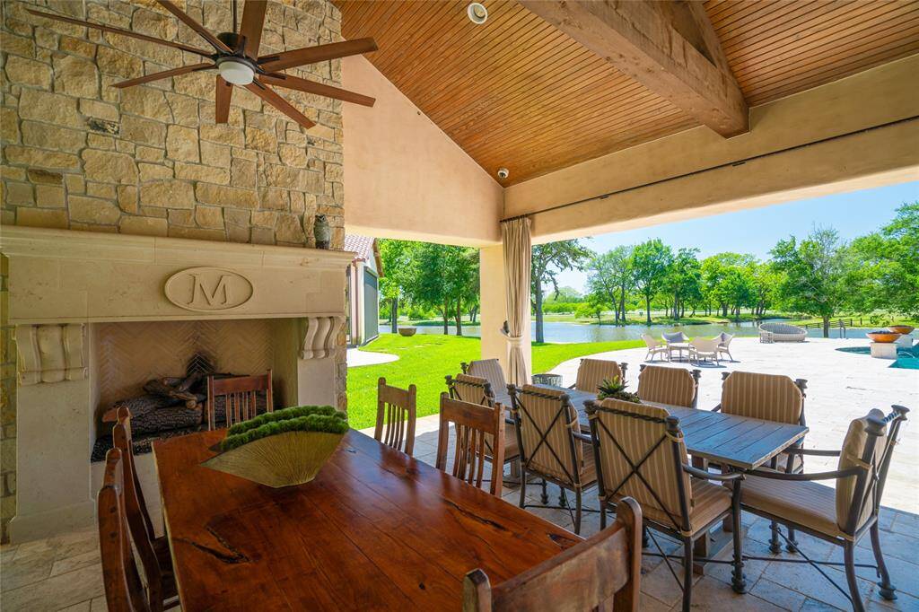 The covered OUTDOOR DINING is located just off the Main House, Pool and Patio areas. Stone tile flooring, pegboard stained wood ceiling with exposed beams/ceiling fans, built-in speakers, stately gas log fireplace (stone surround/mantle) create a relaxed but elegant space to enjoy meals with family and friends. The nearby SUMMER KITCHEN includes stainless Viking gas grill, Elkay stainless sink, griddle space, granite counter.