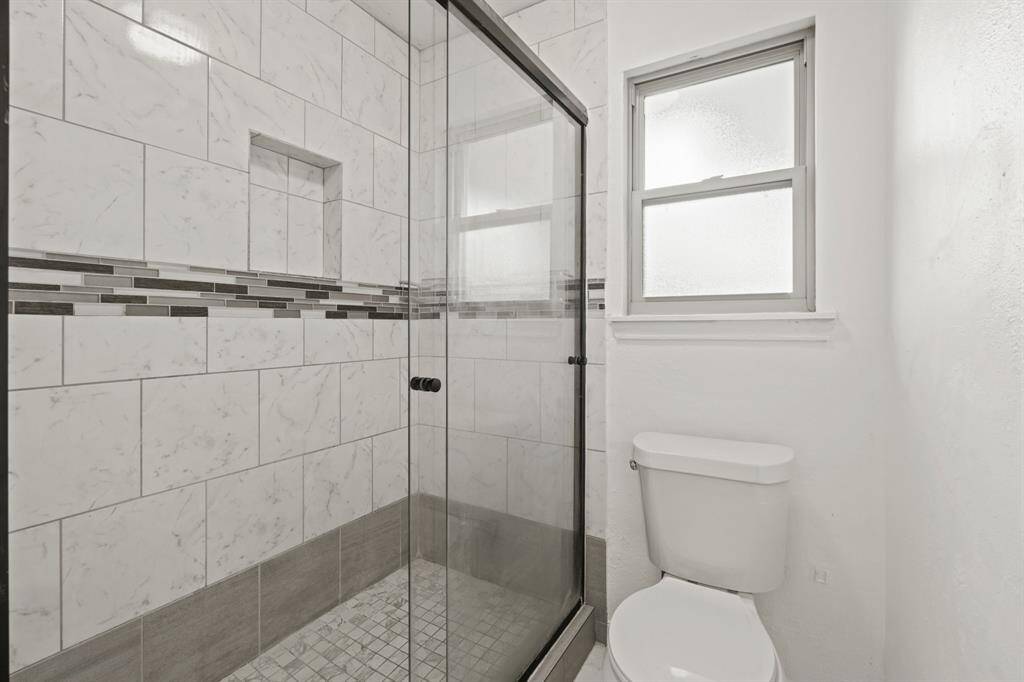 The walk-in shower has tile surround and a sliding glass door.