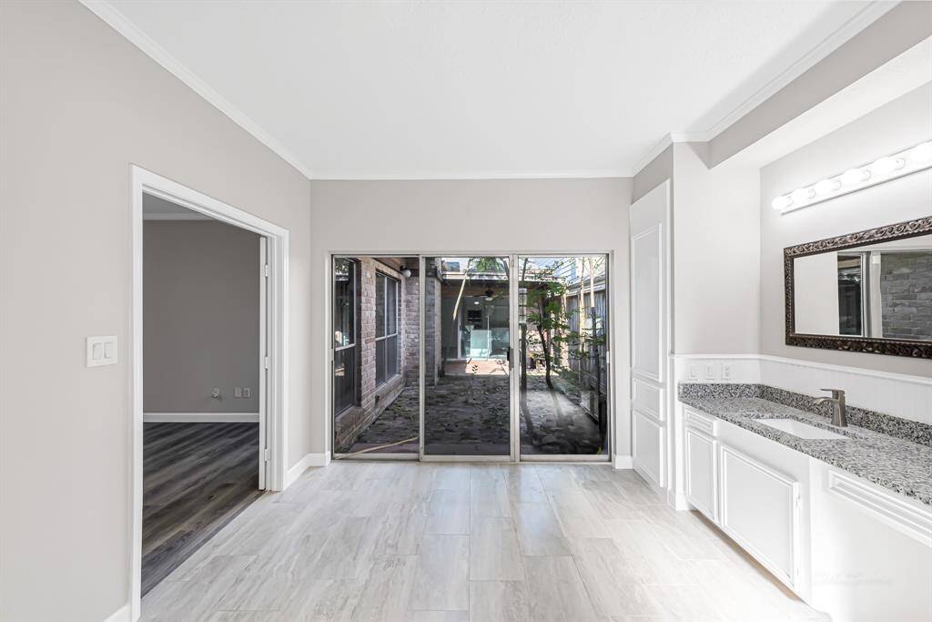 Bright and airy room with large sliding glass doors opening to a patio. Features a modern vanity with granite countertop, neutral walls, and light wood flooring. Ideal for maximizing natural light and indoor-outdoor flow.
