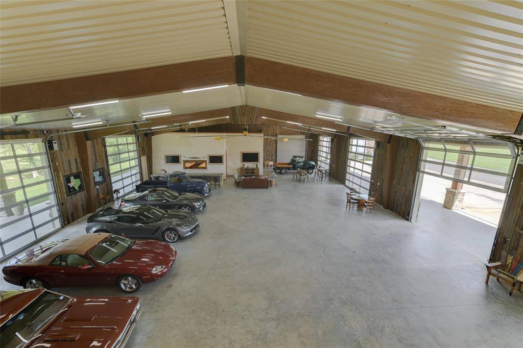 The INTERIOR (100 X 58) includes an over-sized industrial fan, exposed wood beams, metal roofing, concrete flooring, fluorescent lighting, Wet Bar with seating for 6/stone counters and mirrored backsplash/2 stainless sinks/2 Monogram stainless mini-refrigerators/Hushizaki stainless ice maker, 3 TVs, three entrances to the attached housing/dining/kitchen facility, doors to several storage lockers.