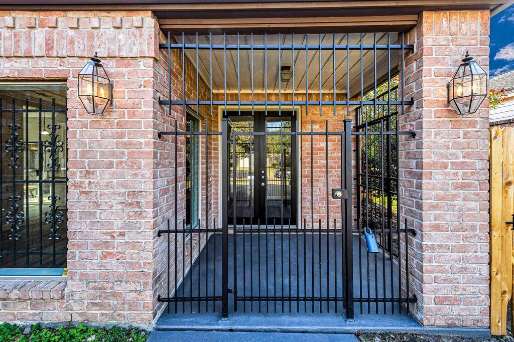 Secure front entrance with a gated porch, featuring brick walls and elegant lantern-style lighting.