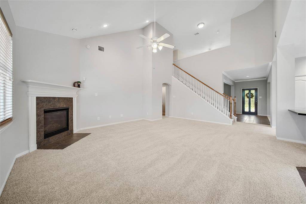 Experience the grandeur of soaring ceilings, cozy up by the elegant corner fireplace, and enjoy the freshness of newly installed carpeting in this inviting living space.