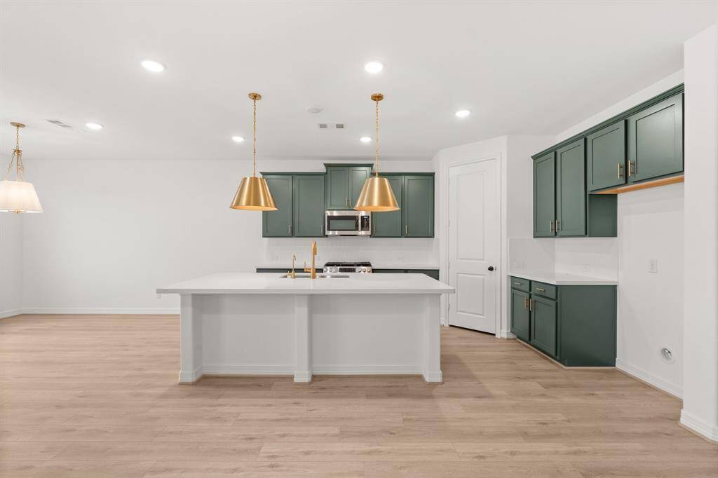 This light and bright kitchen features a large quartz island, custom painted cabinets, a large sink overlooking your family room, recessed lighting, and beautiful backsplash.