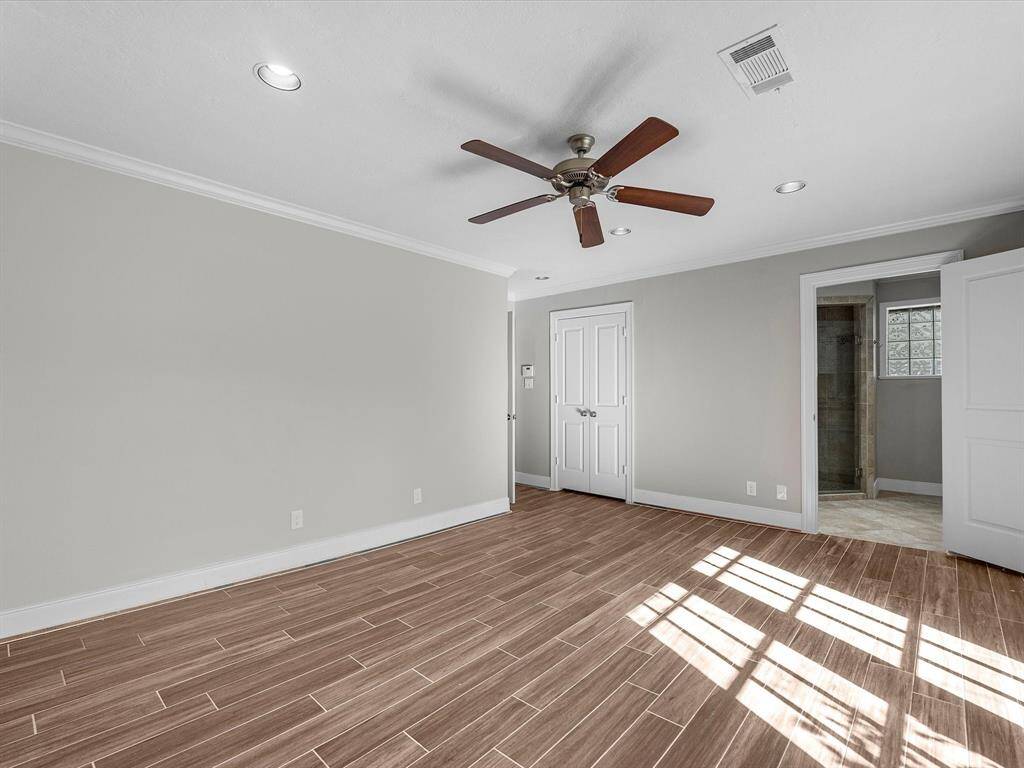 Spacious primary bedroom with elegant flooring and abundant natural light.