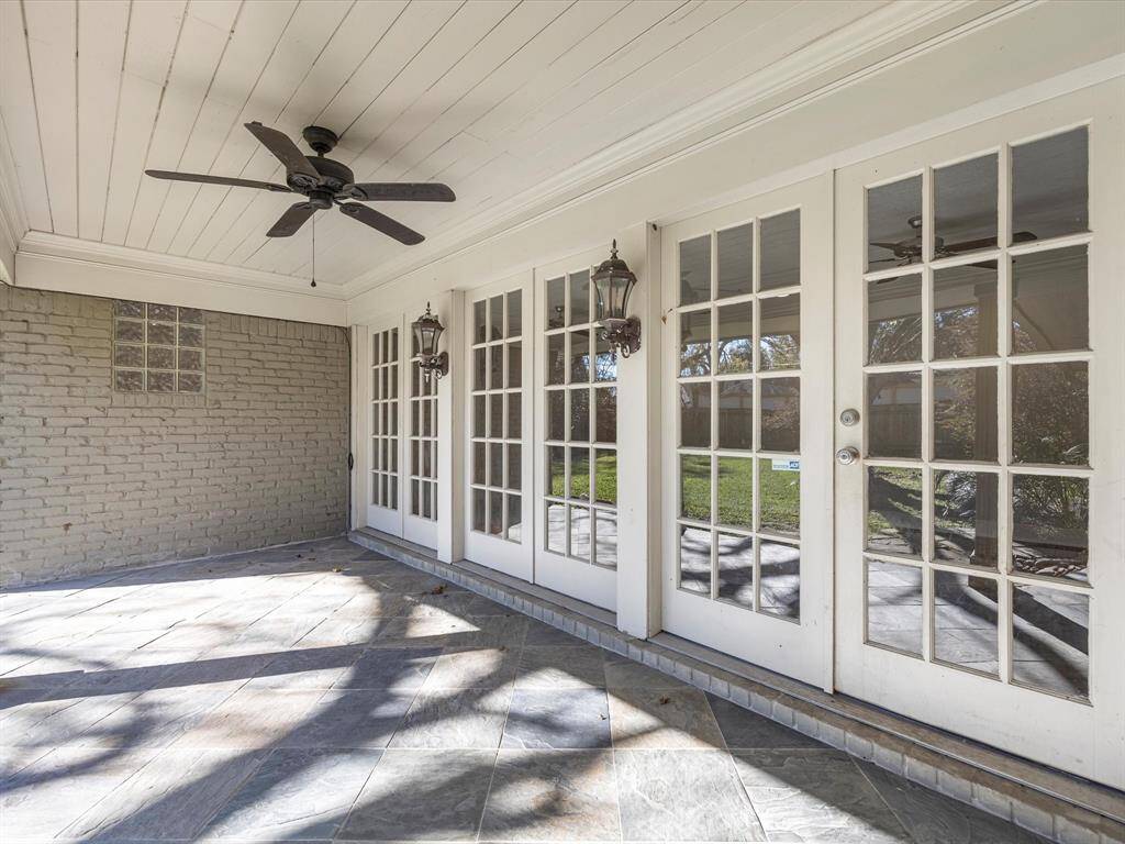 Discover a spacious, slate-tiled patio perfect for outdoor furniture, complete with a ceiling fan and elegant coach lights for a cozy ambiance.