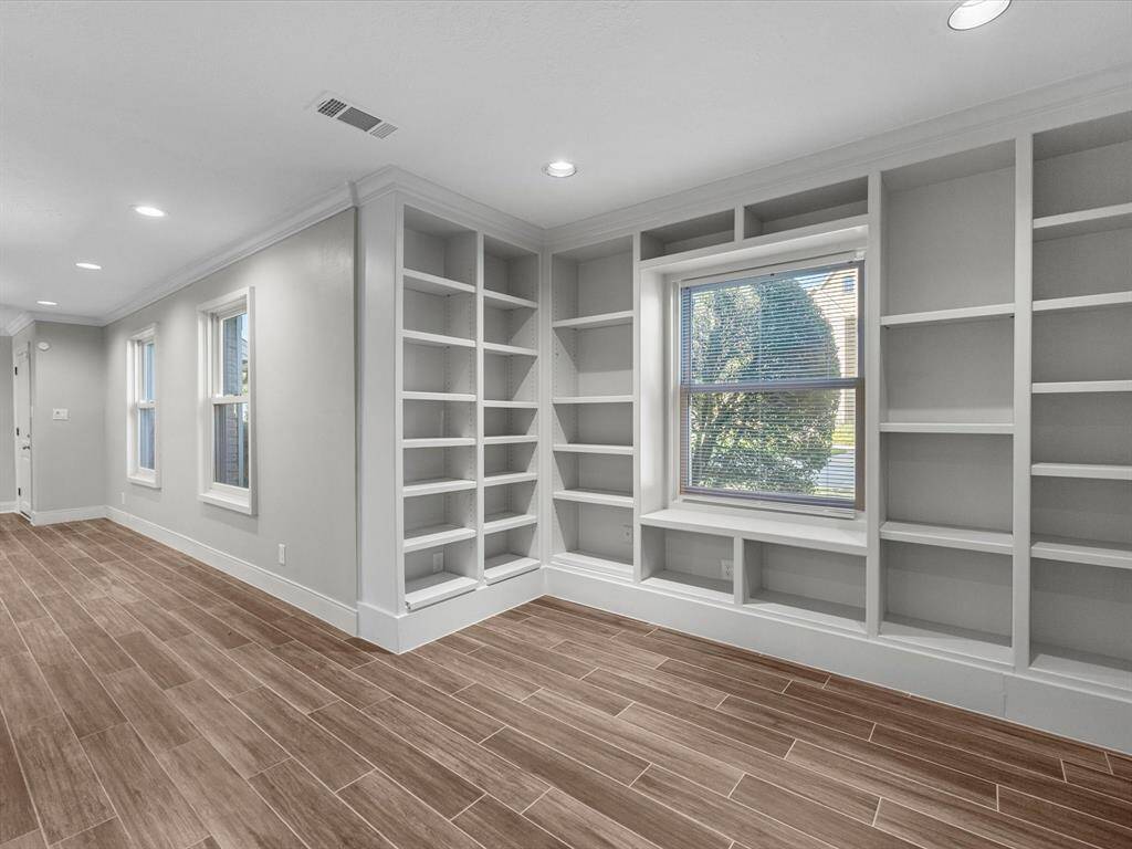 Another view of the bright and spacious office with built-in shelves and abundant natural light.