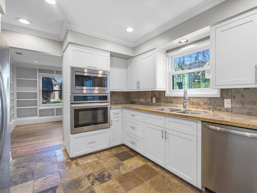 This stylish kitchen boasts high-end stainless steel appliances, including a Frigidaire dishwasher, oven, built-in microwave, and a Whirlpool refrigerator.