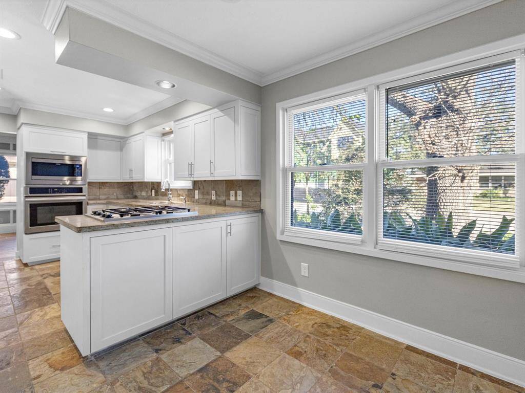 Bright and inviting breakfast room with slate tile floors, fresh grey paint, recessed lighting, crown molding, and extended baseboards.