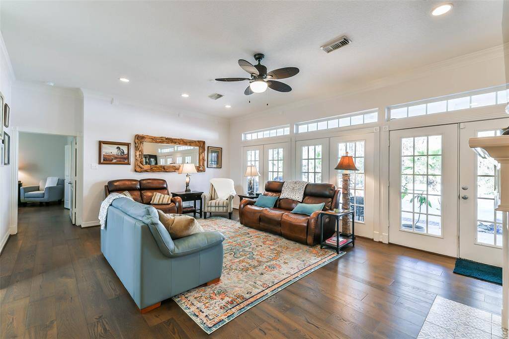 Large living area has a wall of windows and french doors overlooking the backyard and pool