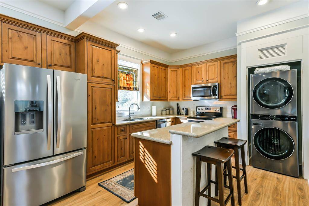 Guest house kitchen with stainless steel appliances and full size stackable washer and dryer