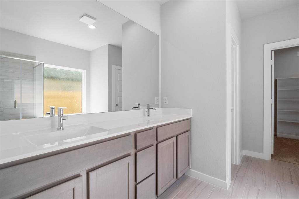 This primary bathroom is definitely move-in ready! Featuring stained cabinets with light countertops and dual vanities, spacious walk-in closet with shelving, high ceilings, custom paint, sleek and dark modern finishes.