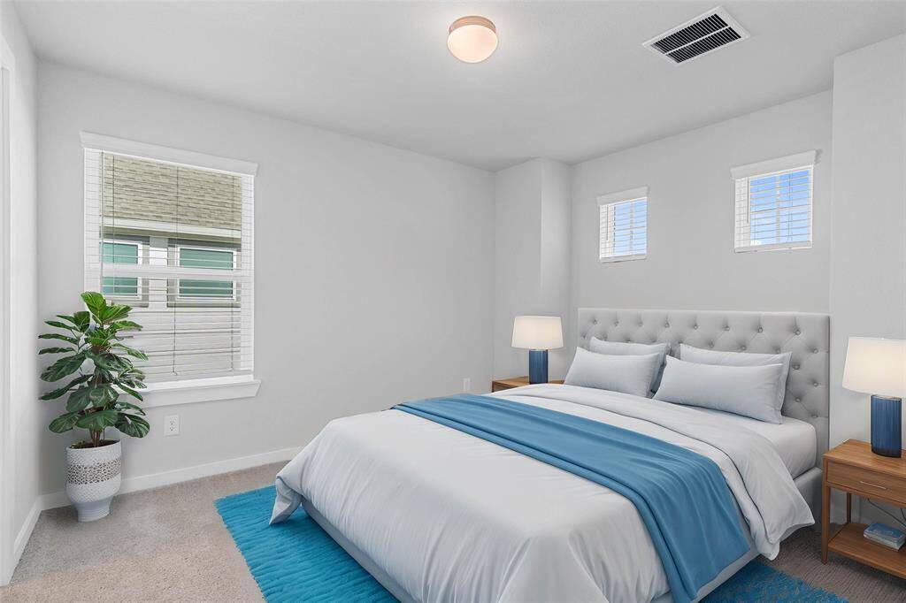 Secondary bedroom features plush carpet, custom paint, lighting, and large windows with privacy blinds.