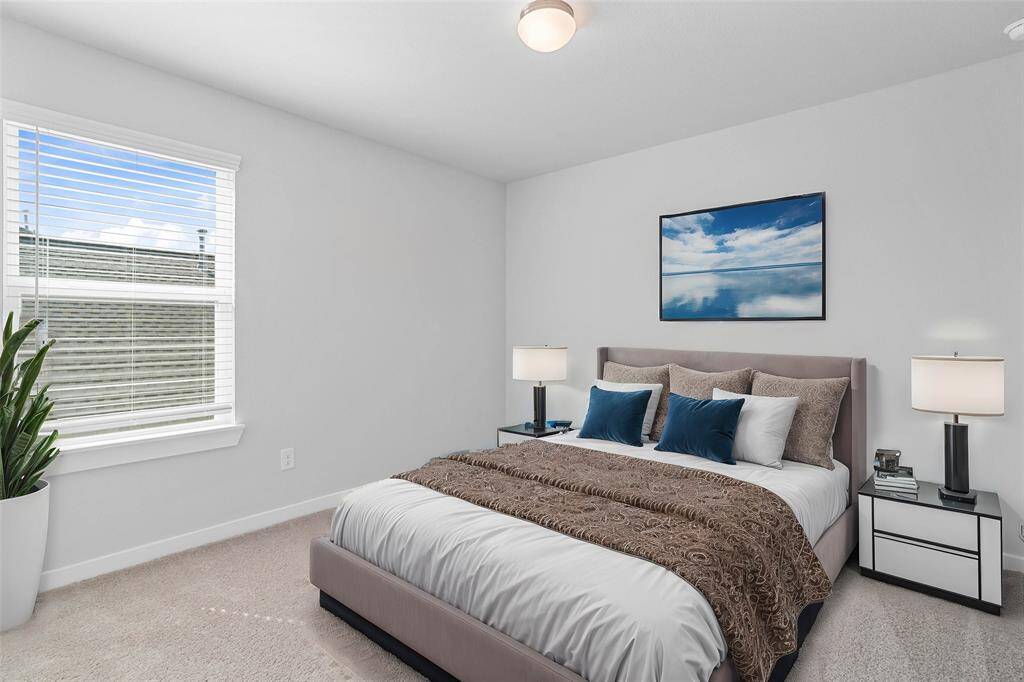 Secondary bedroom features plush carpet, custom paint, lighting, and a large window with privacy blinds.