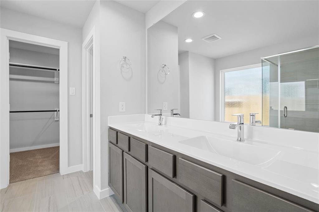 This primary bathroom is definitely move-in ready! Featuring stained cabinets with light countertops and dual vanities, spacious walk-in closet with shelving, high ceilings, custom paint, sleek and dark modern finishes.