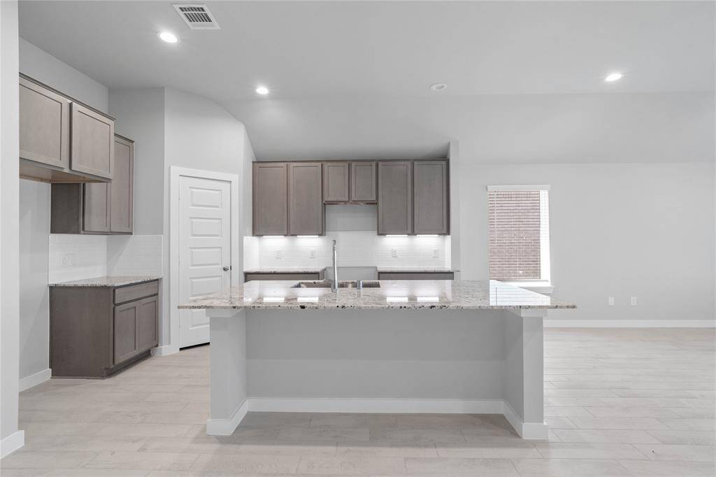 This kitchen is by far any chef’s dream! This spacious kitchen features high ceilings, stained wood cabinets with under cabinet lighting, granite countertops, large kitchen island with extended counter space for a breakfast bar, modern tile backsplash, recessed lighting, and a walk-in pantry all overlooking your huge family room.