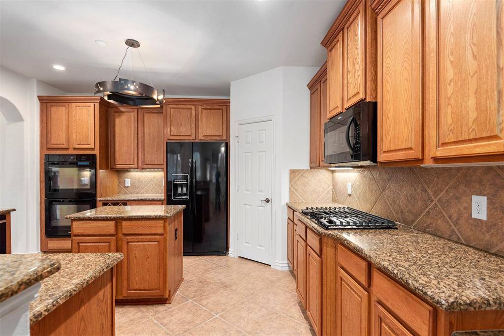 Island kitchen with a gas cooktop and double oven for culinary enthusiasts.