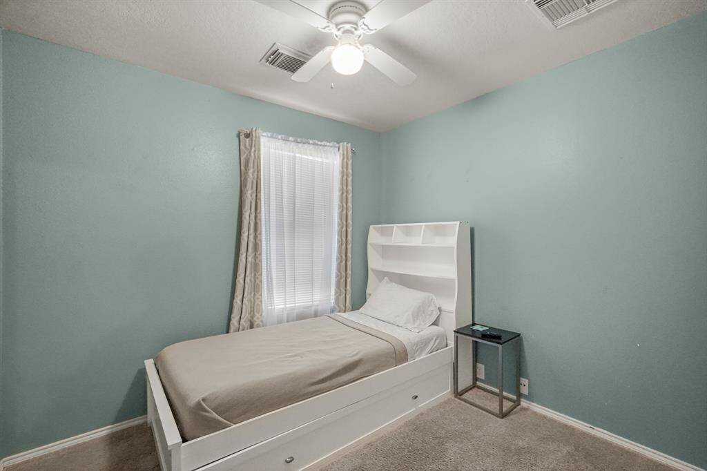 Cozy bedroom with soft blue walls, featuring a single bed with built-in shelves, a small side table, and a window with natural light.
