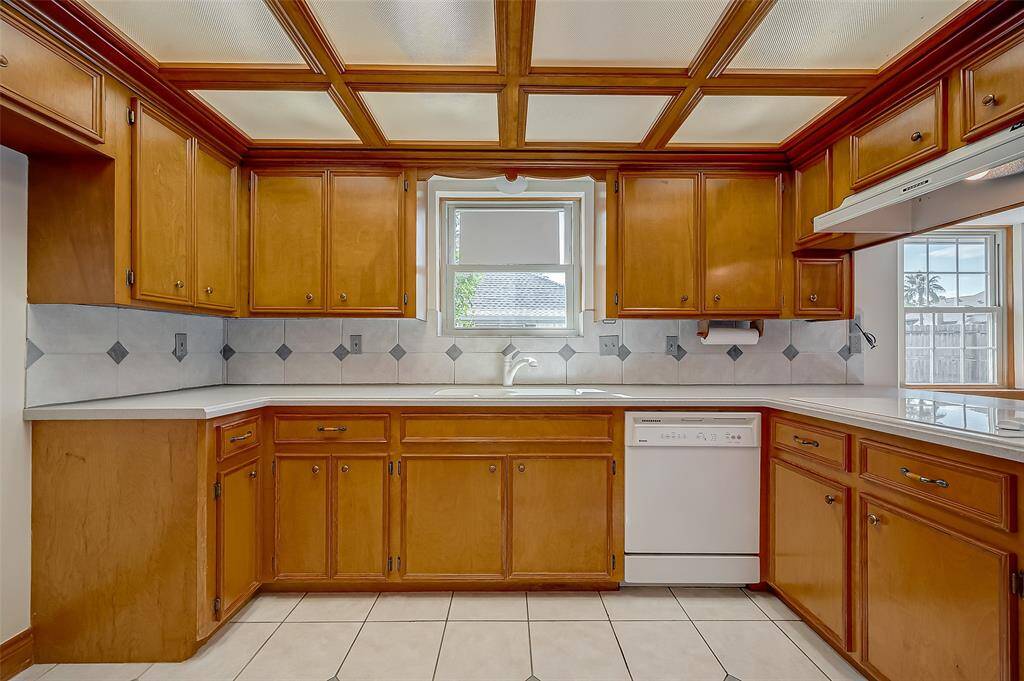 The kitchen, measuring 12.7 x 11.7, features warm honey-colored wood cabinets, elegant Corian countertops, and a stylish tile backsplash. This inviting space combines functionality with a classic aesthetic, making it both practical and visually appealing.