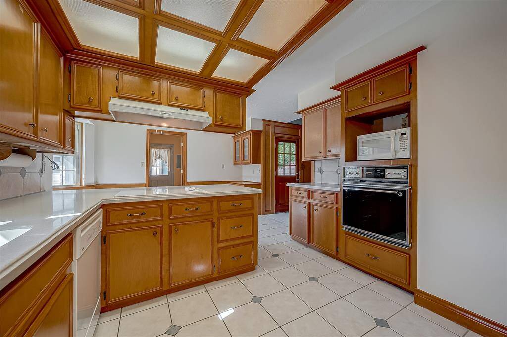 The kitchen features a Whirlpool glass-top cooktop along the peninsula, with ample storage below and practical pots and pans drawers to the right. This layout maximizes efficiency and keeps your cooking essentials organized and within easy reach.