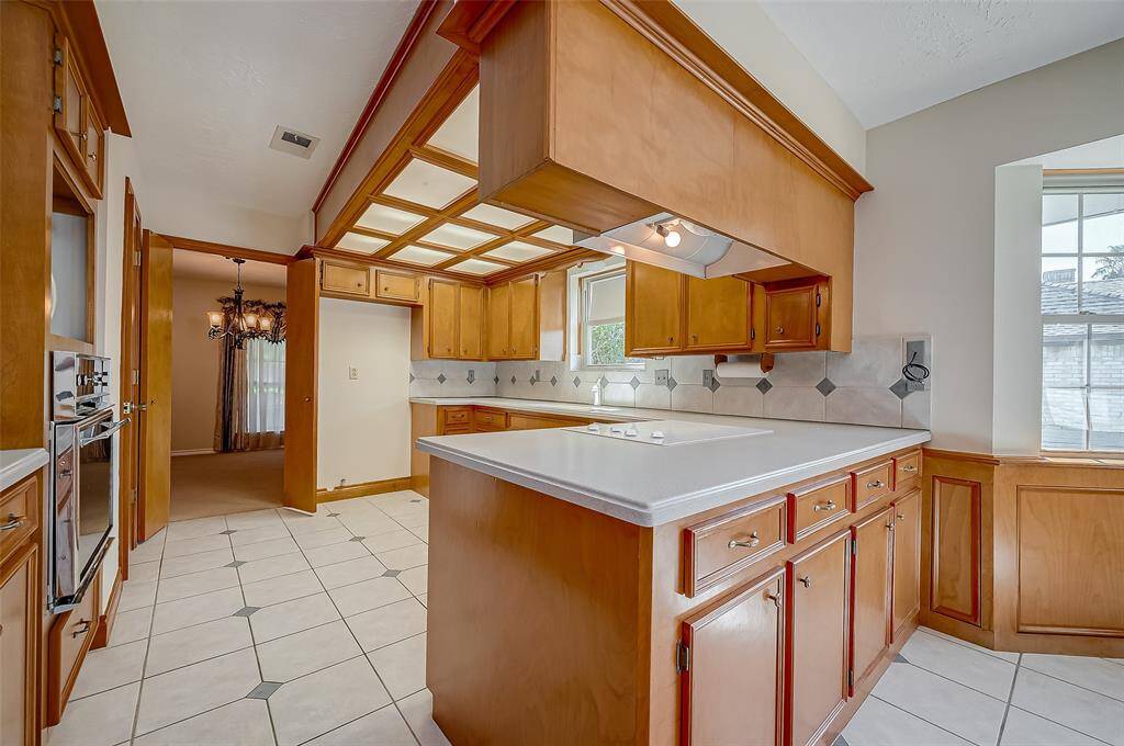 The kitchen peninsula includes additional storage drawers and cabinets on the opposite side of the cooktop, providing extra space for organizing kitchen essentials and enhancing overall functionality.