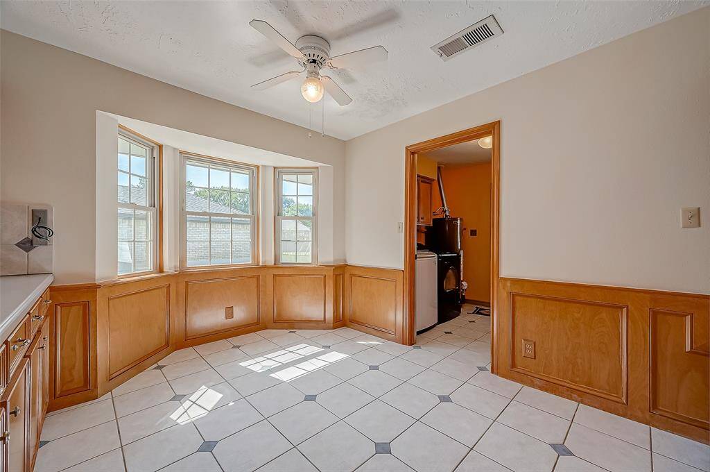 The breakfast room, measuring 13.8 x 8.9, features a bay window overlooking the driveway and side yard, filling the space with natural light. This eat-in area is perfect for casual family gatherings, and the tile flooring makes cleanup easy, especially with little ones around. A door on the right leads to the utility room and a convenient half bathroom.