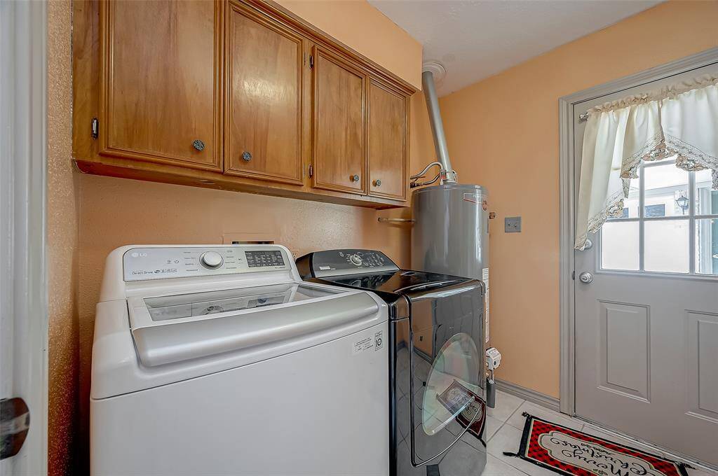 The utility room, measuring 8.3 x 7.7, includes a full-size washer and dryer and is plumbed for both electric and gas dryer connections. It features convenient upper storage cabinets and a Rheem water heater that was replaced in 2018. A door leads to the backyard and the 3-car garage, offering easy access and added functionality.