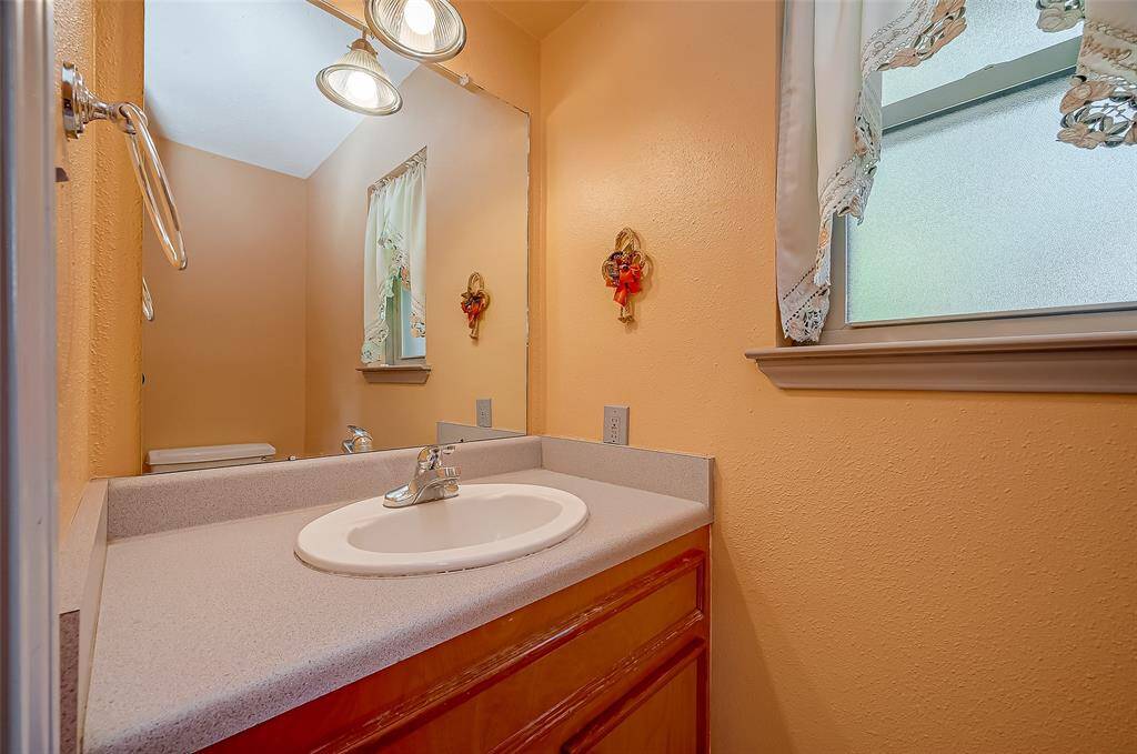 The utility room also includes a half bathroom with a single sink and commode, conveniently located near the back door. This setup is ideal for children playing outside, yard work, or garage projects. It would also be a practical feature if a swimming pool is added to the backyard, providing easy access for guests and family.