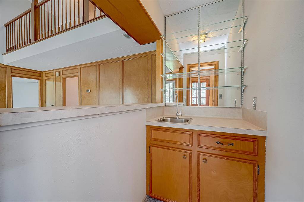 The walk-in wet bar, measuring 5.7 x 3.4, features a single sink with a mirrored wall and glass display shelves, making it ideal for entertaining family and friends during the holidays. Alternatively, this space could easily be repurposed into a second walk-in pantry, offering additional storage and flexibility.