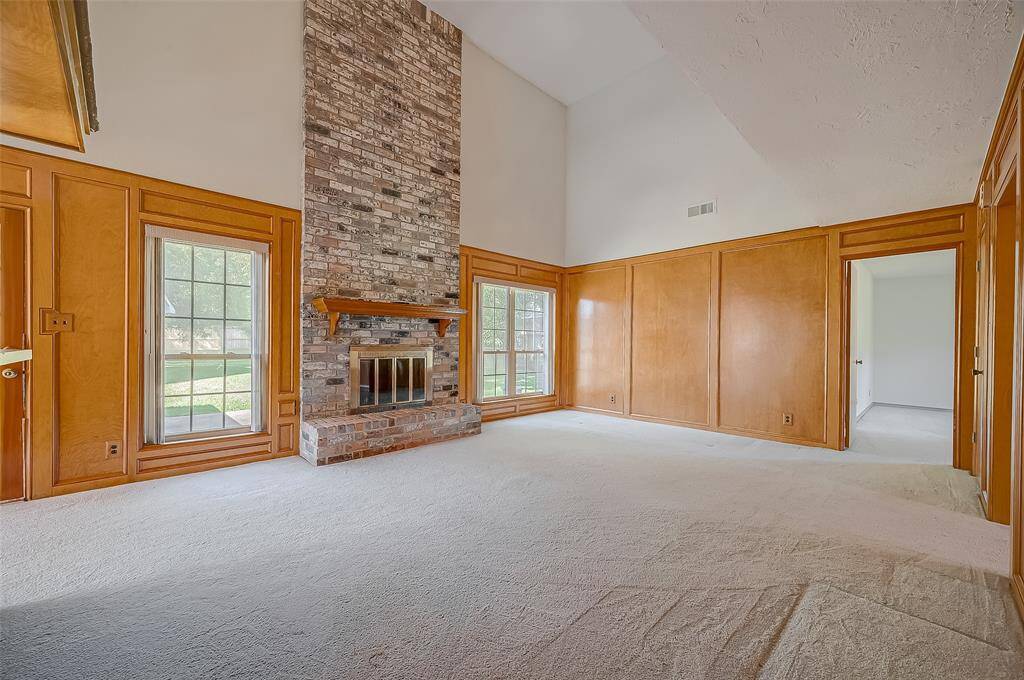 The family room's focal point is the soaring brick fireplace, featuring a wood-burning firebox with a gas starter, a decorative wood mantle, and a classic brick hearth. Glass fireplace doors add a touch of elegance. It’s easy to imagine stockings hanging from the mantle and excited children racing down the stairs on Christmas morning.