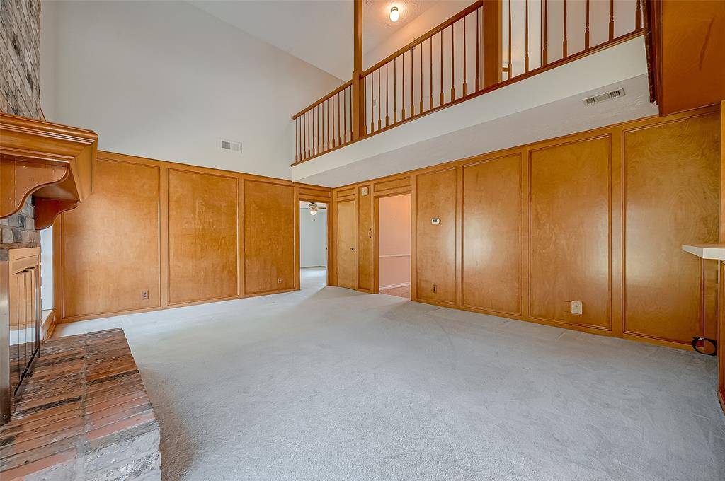 The family room offers abundant wall space for arranging and displaying furniture, with ample room for a sectional sofa. An open doorway at the far end of the room leads to the downstairs owner's suite, providing easy access and a convenient layout.