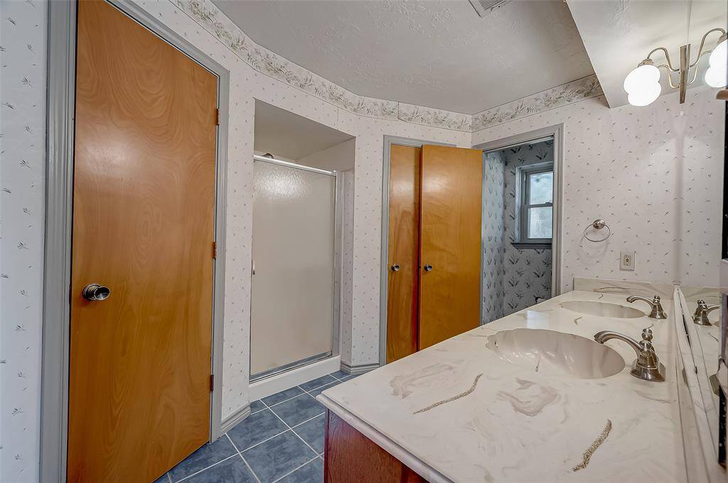 The ensuite bath also includes a walk-in shower, two lighted walk-in closets, and a separate water closet with a commode and window for enhanced privacy and ventilation. The home was replumbed with PEX plumbing in 2009, eliminating concerns associated with aged galvanized plumbing and providing modern, reliable water distribution.