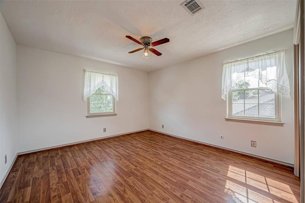 Bedroom #3, measuring 13.1 x 12.1, features wood laminate flooring and a ceiling fan. It includes two windows: one overlooking the front yard and the other facing the side yard.