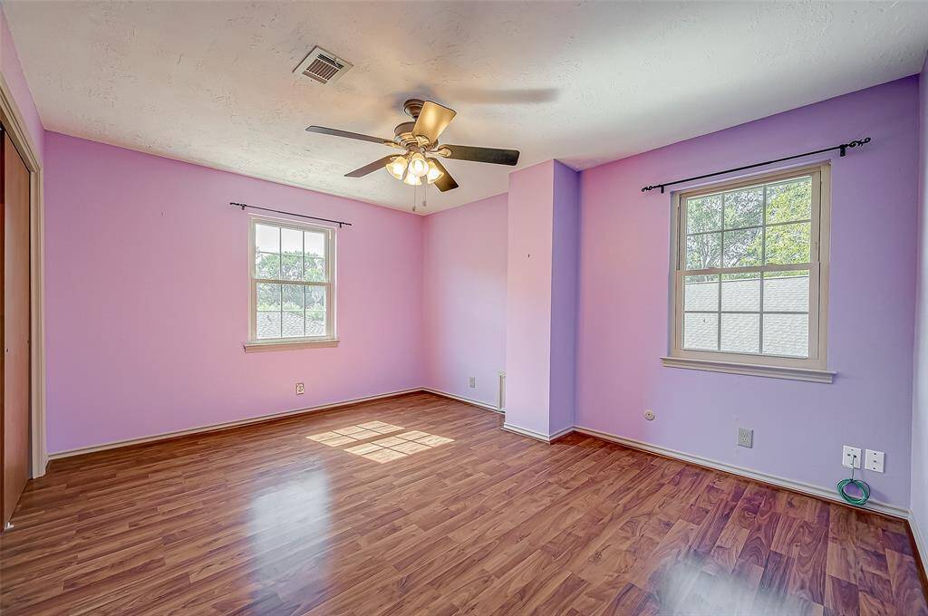 Bedroom #4, measuring 14.2 x 11.3, features wood laminate flooring and a ceiling fan. It includes two windows: one overlooking the side yard and the other facing the backyard.