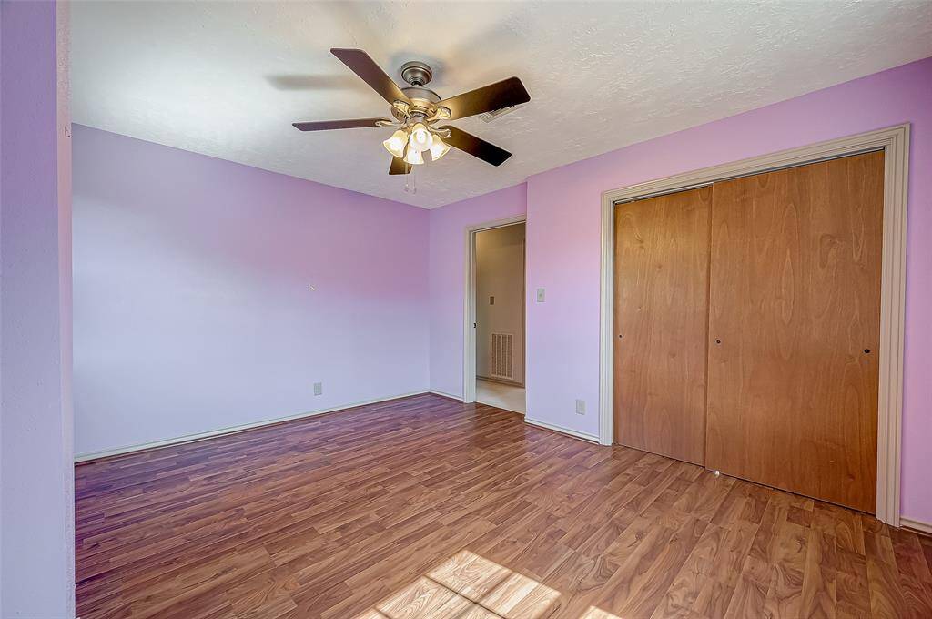 Bedroom #4 features sliding wood doors to the closet, complementing its wood laminate flooring and ceiling fan.