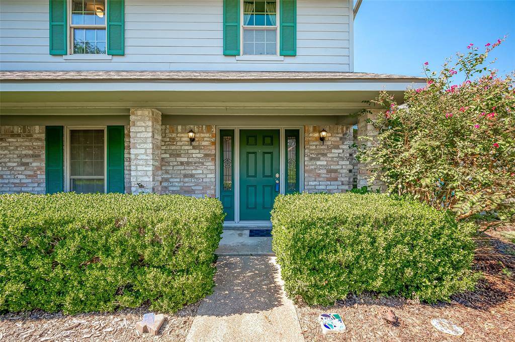 This home's exterior is a combination of brick, durable Hardie board siding, and wood eaves for a timeless, classic look. A simple walkway leads to the front door, framed by two sidelights, while coach lights offer evening illumination. The covered front porch adds both style and functionality, providing a welcoming spot for guests and shelter during inclement weather.