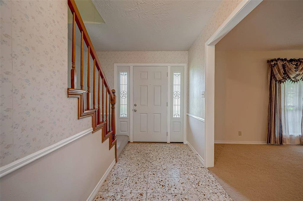 The front door opens into a welcoming foyer featuring original Terrazzo tile flooring and elegant chair-rail molding. With a traditional floorplan, the foyer seamlessly flows into formal living and dining rooms, creating a timeless and inviting atmosphere for guests.