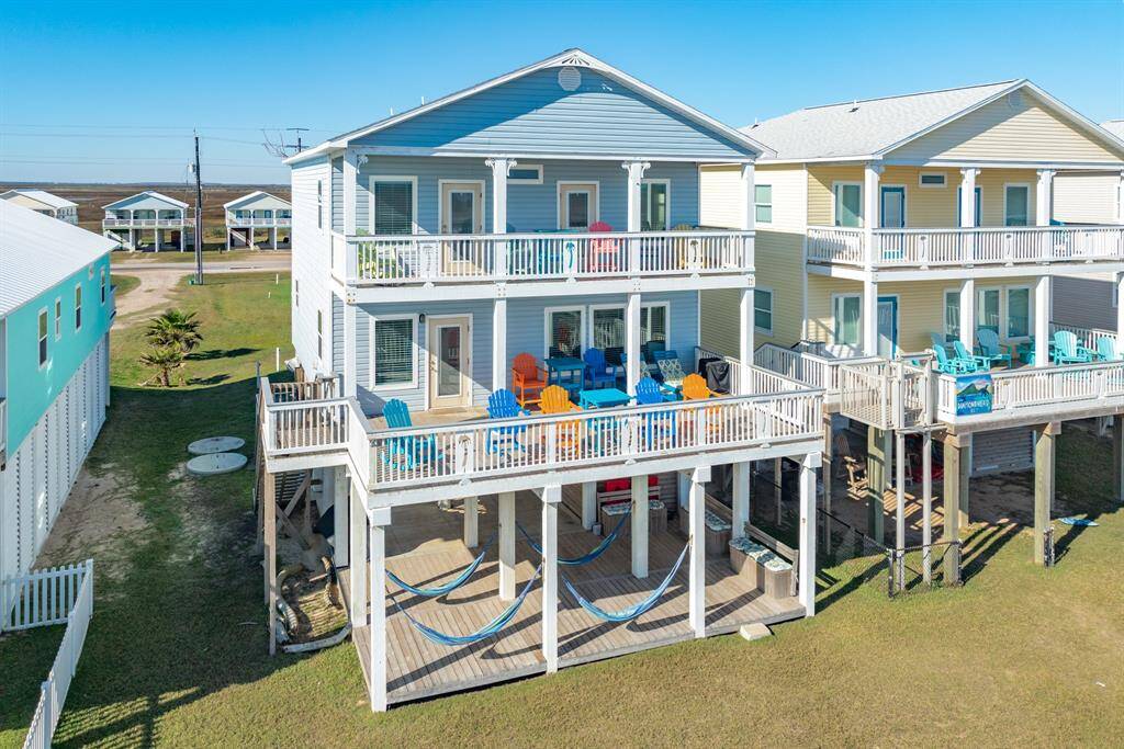This charming stilted beach house features a spacious two-story design with multiple decks for outdoor relaxation. It includes colorful outdoor furniture and hammocks, perfect for enjoying the coastal breeze. Located in a serene neighborhood, it's ideal for beach lovers seeking a vibrant, inviting home.