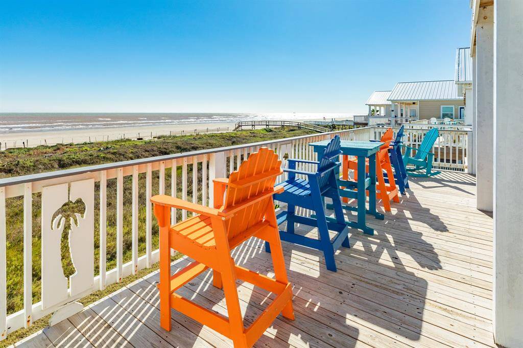 2930 Bluewater features a spacious wooden deck with colorful chairs, offering stunning gulf views and direct beach access. Perfect for relaxing and enjoying beachside living.