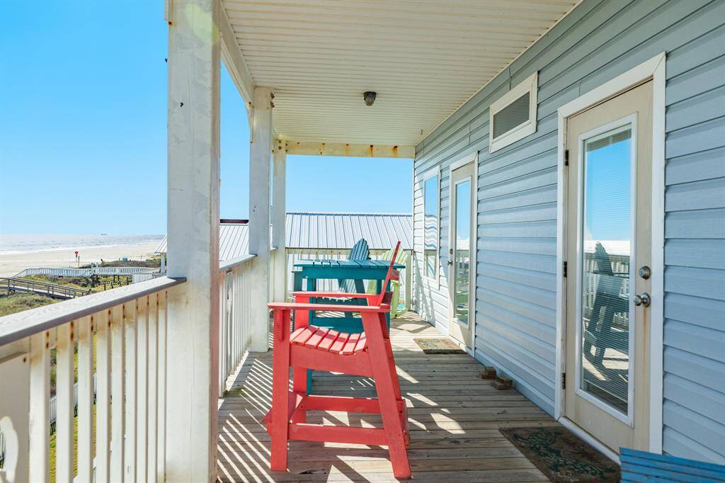 This photo shows a coastal home's covered deck with colorful outdoor seating and a view of the beach, perfect for relaxing and enjoying ocean breezes.