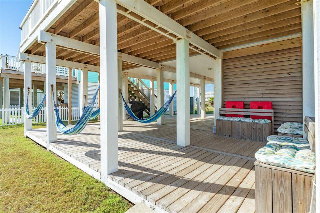 A spacious, ground floor covered wooden deck area with multiple hammocks and cushioned seating, perfect for relaxation and outdoor enjoyment.