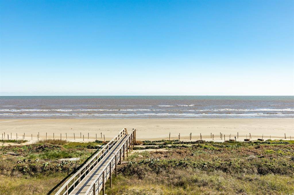 A serene beachfront view with a wooden walkway leading to a sandy beach, perfect for ocean lovers seeking tranquility and direct beach access.
