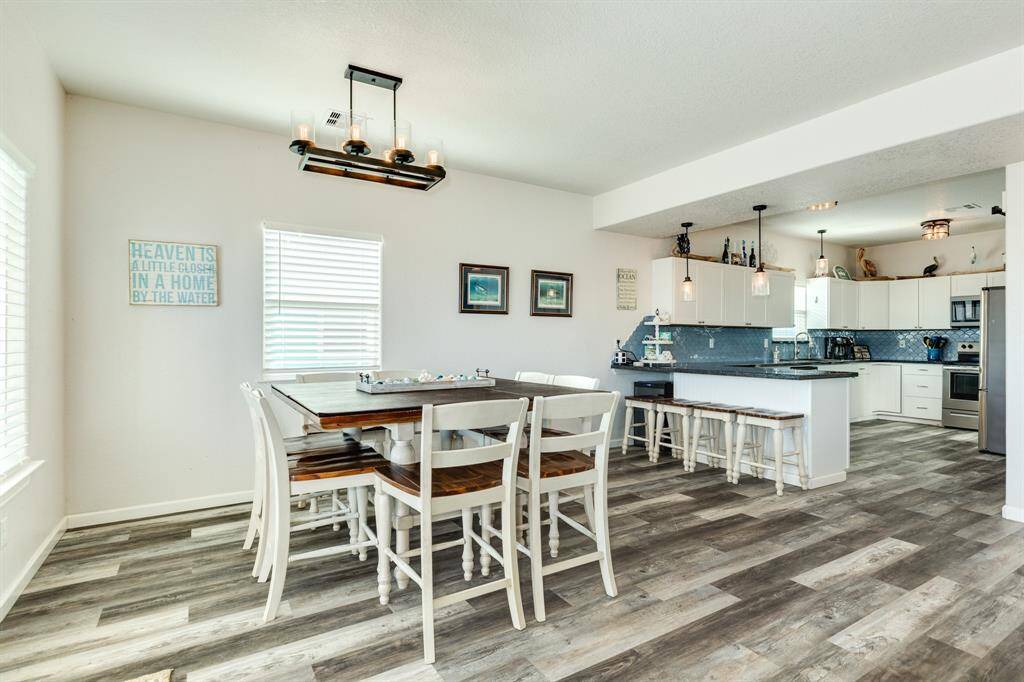 Bright and airy open-concept kitchen and dining area with modern lighting, stylish flooring. The kitchen features white cabinetry, granite counters, upgraded lighting  and granite for bar seating.